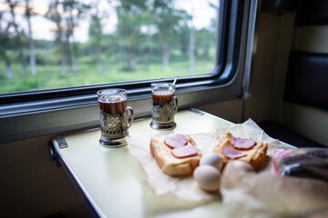 Train food pastry and tea on table in long distance car by window. Travel meal, railway snack, tourism comforts, dining car amenities, locomotive cuisine, snack options, transportation hospitality