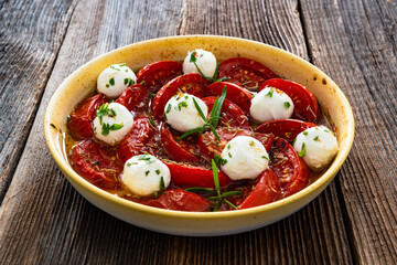 Roasted tomatoes and labneh cheese salad on wooden table