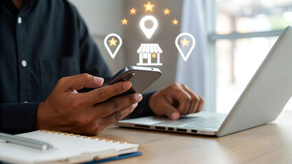 Businessman uses a smartphone while working on laptop with holographic overlay showing a storefront icon, location pin, and five star rating