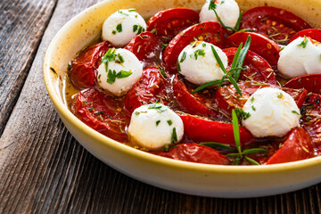 Roasted tomatoes and labneh cheese salad on wooden table