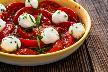 Roasted tomatoes and labneh cheese salad on wooden table