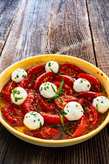 Roasted tomatoes and labneh cheese salad on wooden table