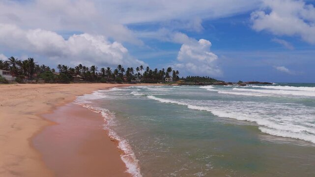 Ocean Waves Touching Shoreline Under Bright Sky Side Scrolling Drone Shot