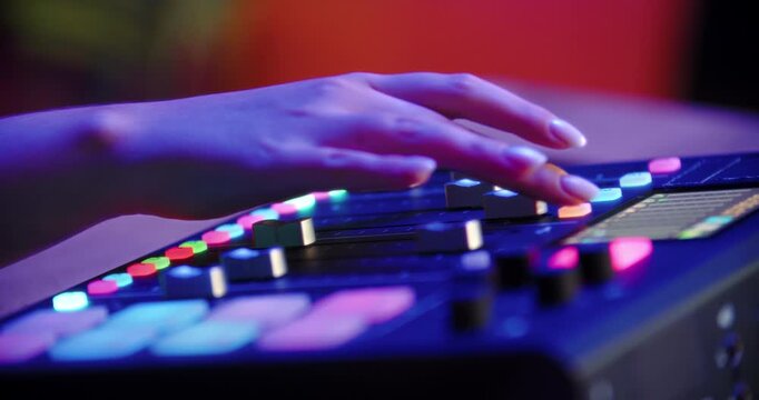 Fingers adjusting faders on digital audio console