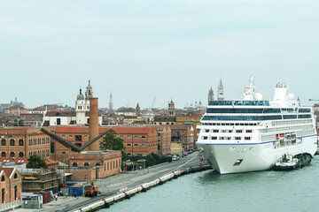 Large cruise ship docked in the historical center of Venice near centuries-old buildings. The imposing vessel dominates the fragile skyline of the UNESCO World Heritage city.