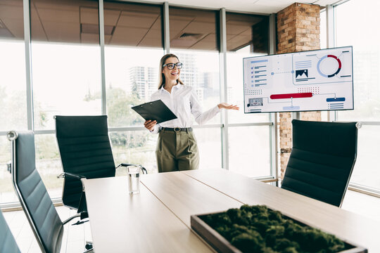 Young businesswoman presenting a corporate analysis during a meeting in a modern office with bright indoor lighting - Powered by Adobe