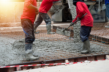 Workers are pouring concrete and cement at the construction site.