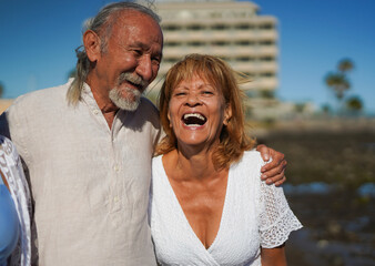 Fototapeta premium Happy senior couple having fun together on the beach during summer vacation - Elderly people lifestyle, love and travel holiday concept