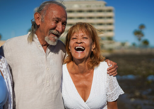 Happy senior couple having fun together on the beach during summer vacation - Elderly people lifestyle, love and travel holiday concept