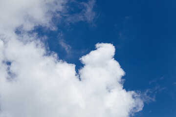 Fluffy white clouds scattered across a bright blue sky, creating a serene atmosphere, perfect for backgrounds or nature-themed designs with copy space