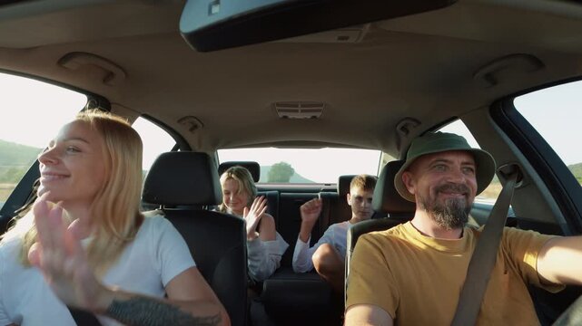 Family members enjoying road trip, singing and dancing together while father drives, creating joyful moments during summer vacation journey