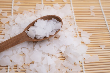 Close-up of magnesium salt flakes. Spa body care and magnesium therapy. White salt, cotton towels,...