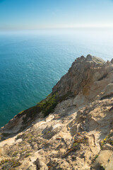 A steep rocky cliff descends toward the deep blue Pacific Ocean at Point Reyes National Seashore, California.