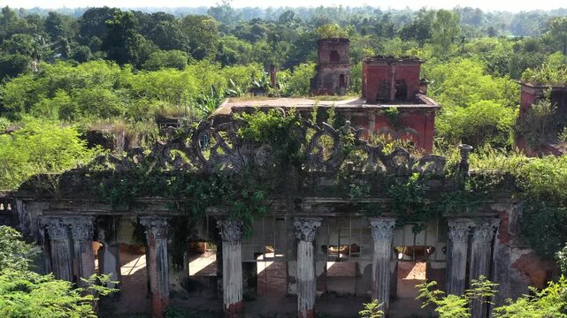 Naogaon, Bangladesh - 22 August 2025: Aerial view of the decaying Dubolhati Rajbari ruins, where red brick structures are being reclaimed by the lush, green overgrowth.
