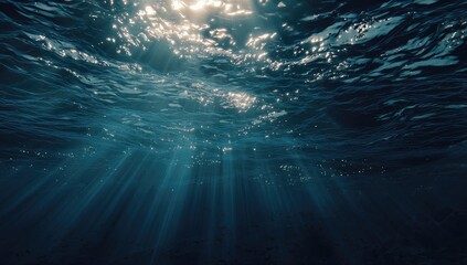 Sunbeams penetrate deep ocean water, illuminating particles and creating a dramatic, ethereal underwater scene