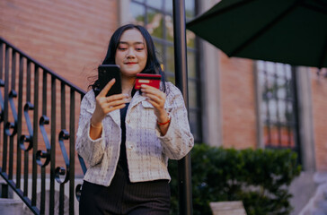 Fototapeta premium Asian businesswoman doing online payment via smart phone and credit card. Web subscriptions e-commerce, checking electronic wallet balance, e-banking and online transactions.