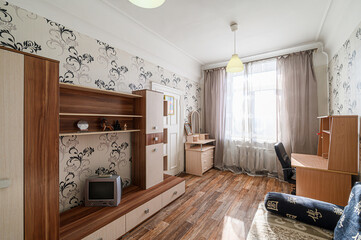 Cozy room with floral wallpaper, wooden furniture, and natural light streaming through the window. A comfortable, lived-in space