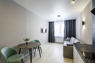 modern apartment featuring a dining area with round table and two chairs, a comfortable sofa by the window, and a sleek kitchen corner