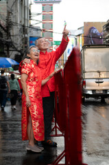 A happy senior couple strolls along a Chinatown in Bangkok, Thailand,