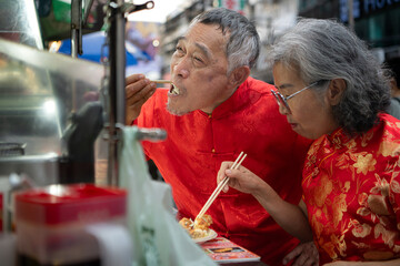 A happy senior couple strolls along a Chinatown in Bangkok, Thailand,