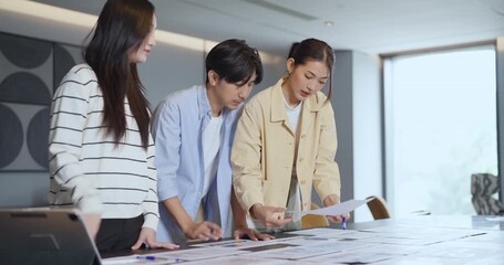 Three young business people discussing report and financial charts during office meeting, analyzing business data and planning marketing strategy for company teamwork success - Powered by Adobe