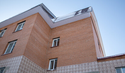Brick residential building with tiled roof and snow, blue sky, horizontal low angle, worm eye view, low angle