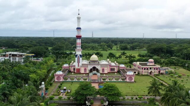 Barishal, Bangladesh - 22 August 2025: Aerial view of the Baitul Aman Jame Masjid Complex stands amidst green lawns, its pink and white facade contrasting with the verdant trees.