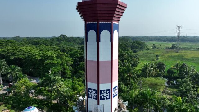 Barishal, Bangladesh - 22 August 2025: Aerial view of a minaret with blue tiled roof rising above a lush green landscape, creating a striking contrast.