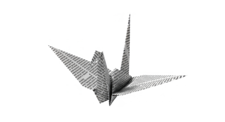 A paper crane origami sculpture, textured with printed text, isolated on a white background.