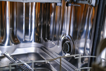 Open built-in dishwasher machine with empty space in modern yellow kitchen. Front view, vertical.
