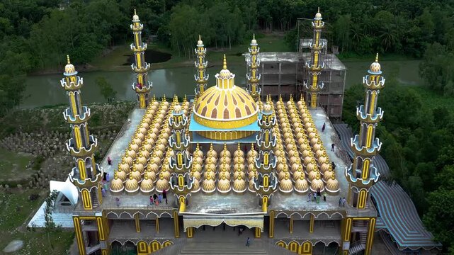 Tangail, Bangladesh - 22 August 2025: Aerial view of the majestic 201 Dome Mosque, its golden domes shimmering against the lush green backdrop of the surrounding landscape.