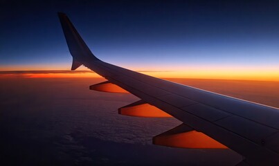 Obraz premium Sunset view from airplane window, wing silhouette against fiery sky and cloud cover