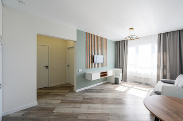 Modern apartment interior with sofa, table, chairs, TV, and natural light. Minimalist design, clean lines