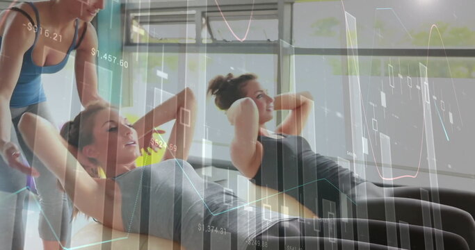 Fitness trainer in sportswear assisting clients performing crunches in studio, with padded benches