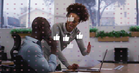 Collaborating business professionals working at office desk, with laptop documents thumbs-up icons