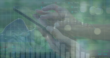 Tapping hands in business shirts on phone touchscreen at trading desk, with financial charts