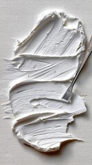 Creamy white texture spread across canvas with a metal palette knife in an artistic setting