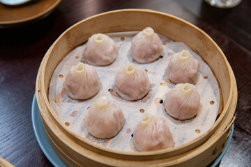 Traditional steamed soup dumplings served in bamboo steamer, translucent wrappers revealing rich broth inside, Chinese dim sum delicacy