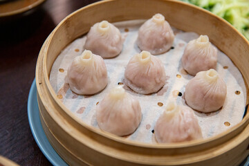 Hot soup dumplings with thin skins arranged neatly in bamboo steamer, classic Chinese dim sum served fresh with visible steam lines