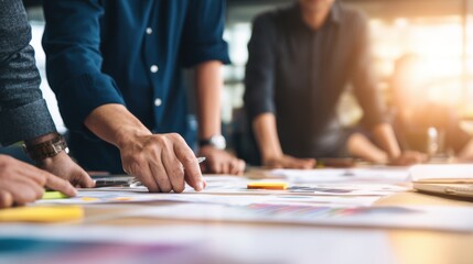 Team collaborating on creative project at modern workspace with colorful designs and notes on table