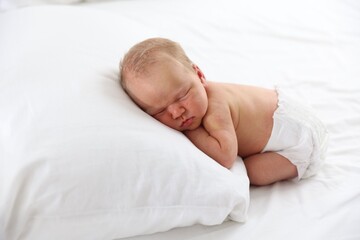 Cute newborn baby sleeping on bed indoors