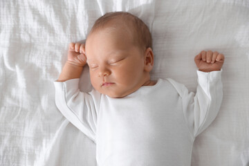 Cute newborn baby sleeping on bed, top view