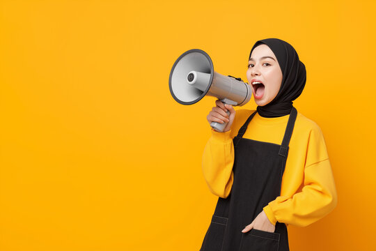 A young woman wearing a hijab, a yellow shirt, and a black apron holds a megaphone with a surprised expression. The image symbolizes communication, announcement, and empowerment.