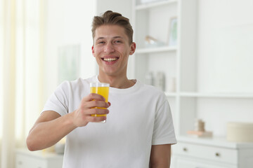 Fototapeta premium Smiling man with glass of orange juice at home. Refreshing drink