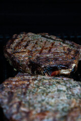 Well grilled huge steak on BBQ gas grill searing hot with grill marks crossed, and lots of seasoning.