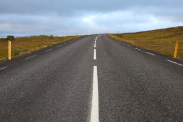 Straight asphalt road disappearing into the distance in Icelandic highlands. Minimalist travel and transport concept showing open road, freedom, and remote wilderness.