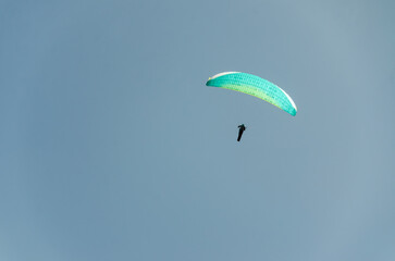 Paraglider flying high above the mountains with stunning panoramic views. Adventure and extreme sport.