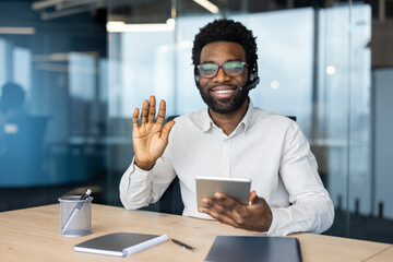 Smiling professional using a tablet and headset during an online meeting