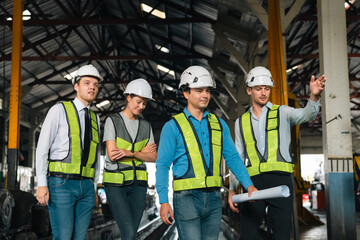 Engineers wearing safety helmets inspecting railway blueprint beside a vintage locomotive, symbolizing teamwork, innovation, and development in modern rail transportation and infrastructure projects