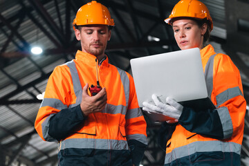 Engineers wearing safety helmets inspecting railway blueprint beside a vintage locomotive, symbolizing teamwork, innovation, and development in modern rail transportation and infrastructure projects